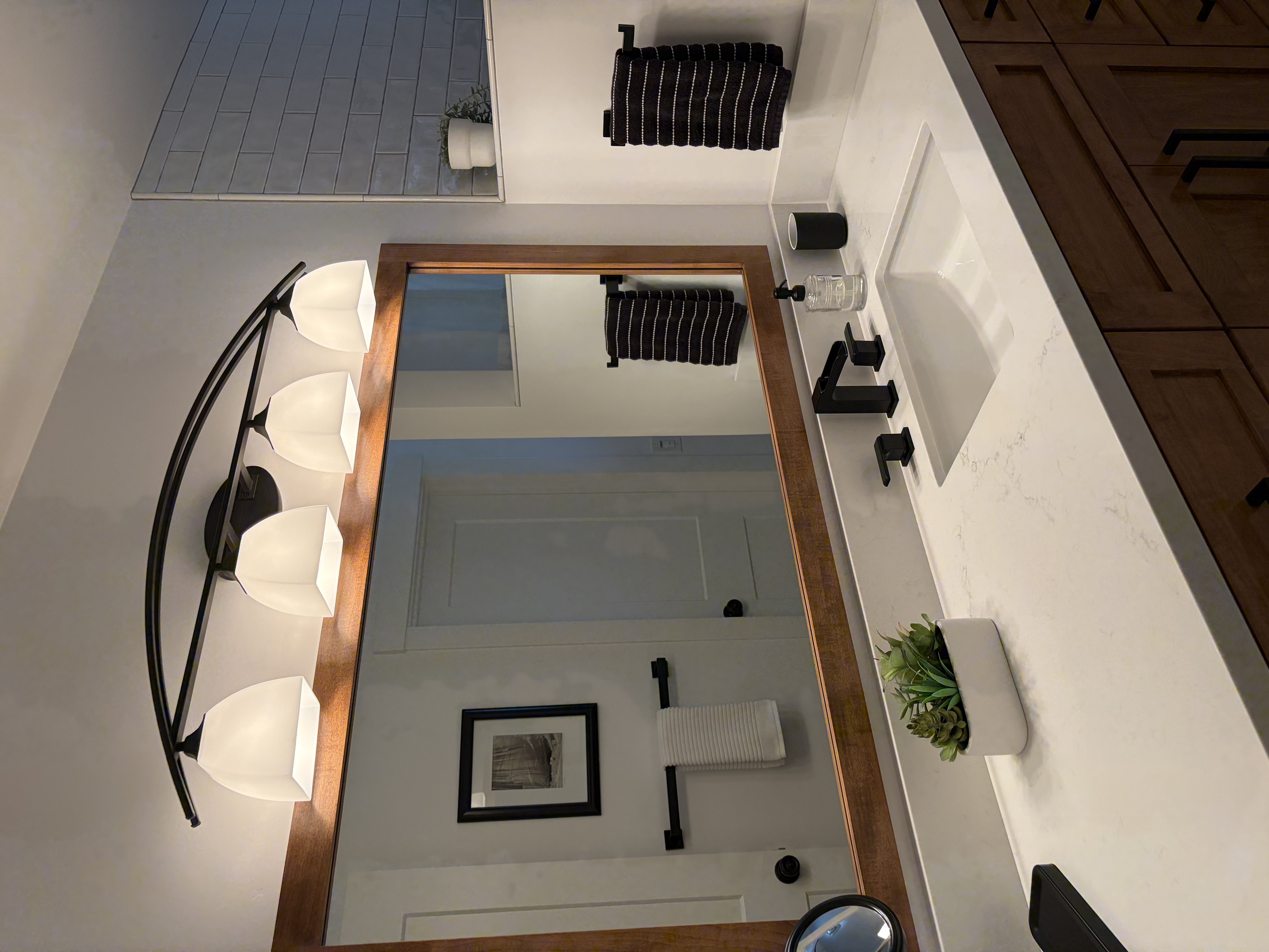 Bathroom vanity with wood-framed mirror and wall sconces