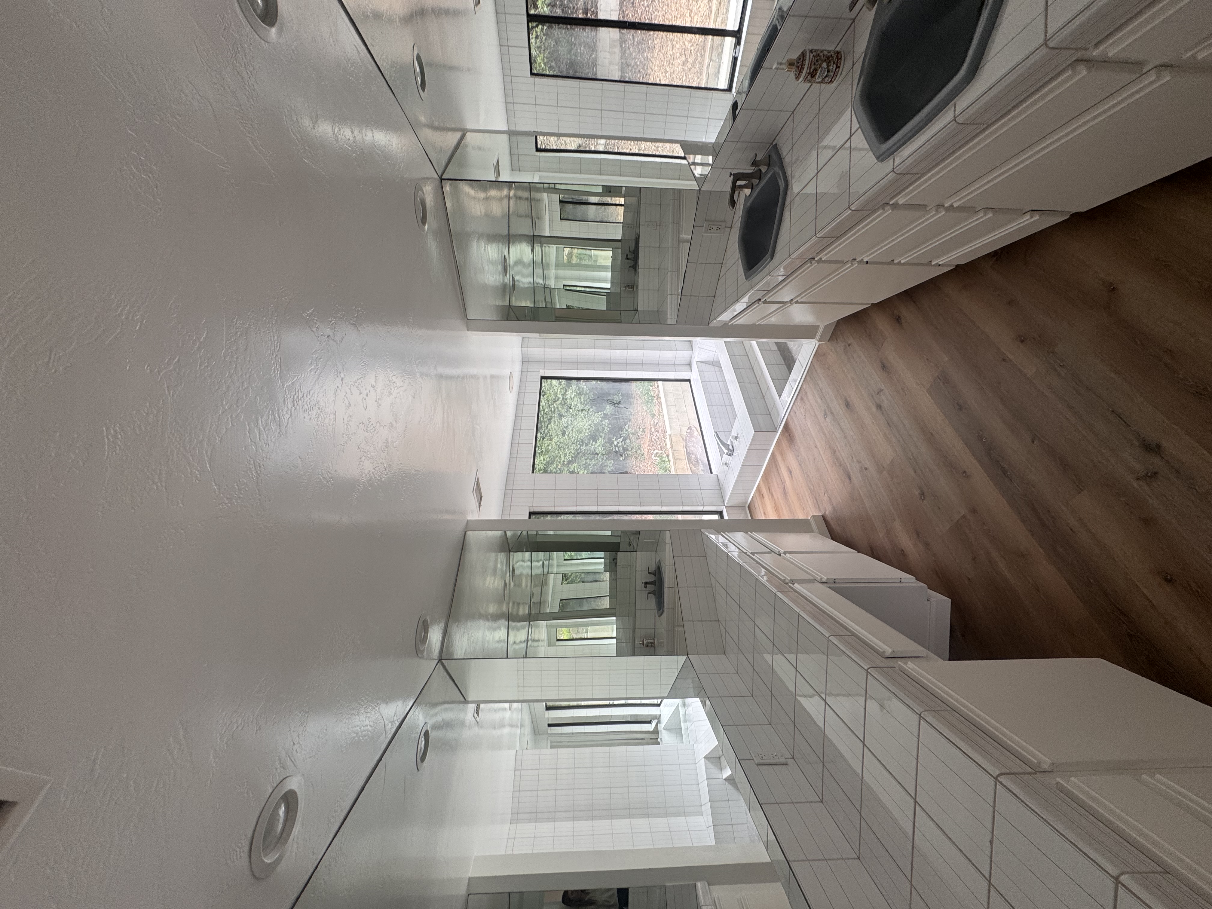 White tile bathroom with glass shower and wood floor