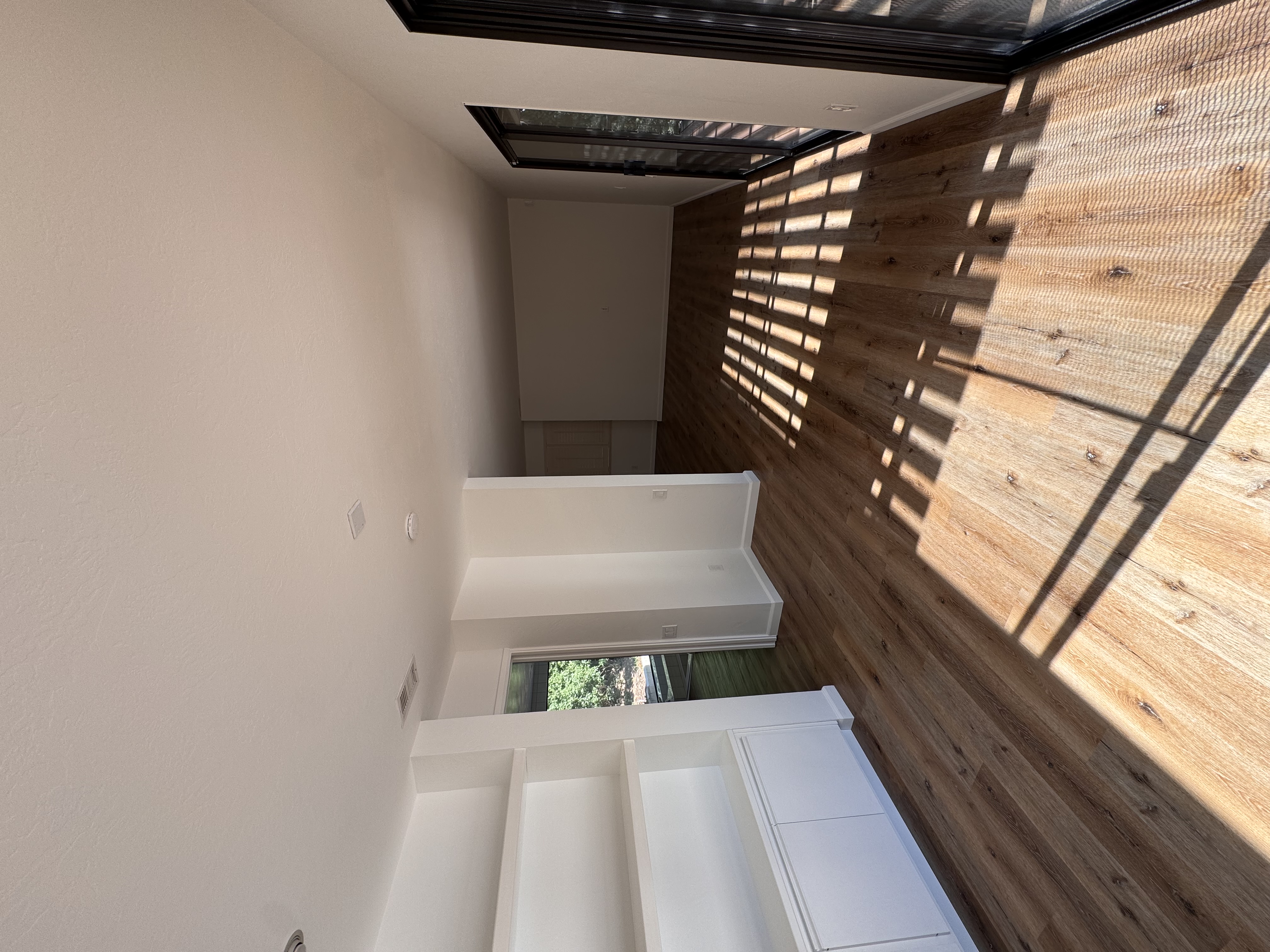 Open living area with wood accent wall and skylights