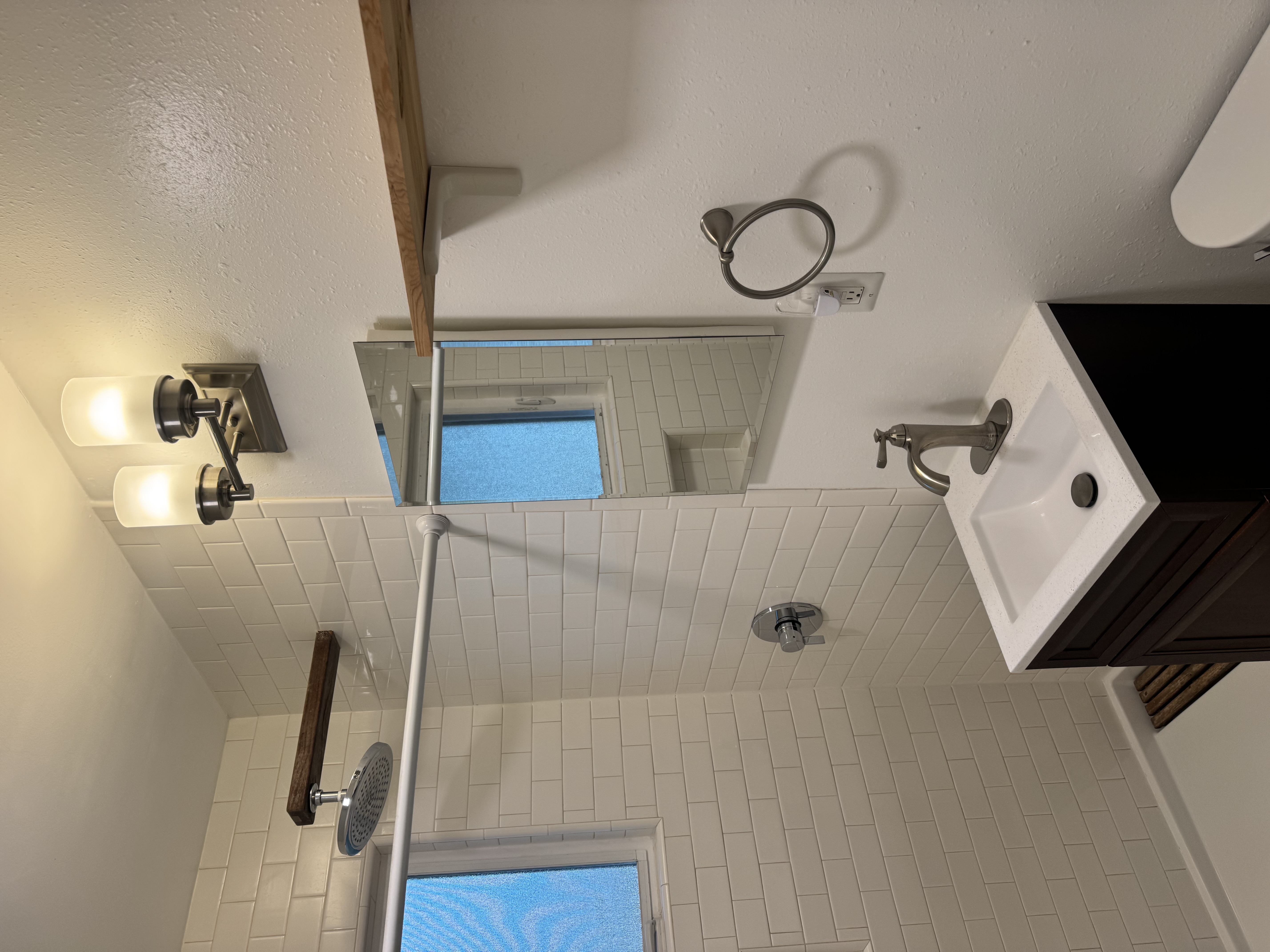 Bathroom with open shower, sconce lighting, and vessel sink